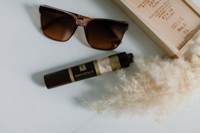 Eminence Organics Sun Defense Mineral Powder with pompas grass and sunglasses laying beside it