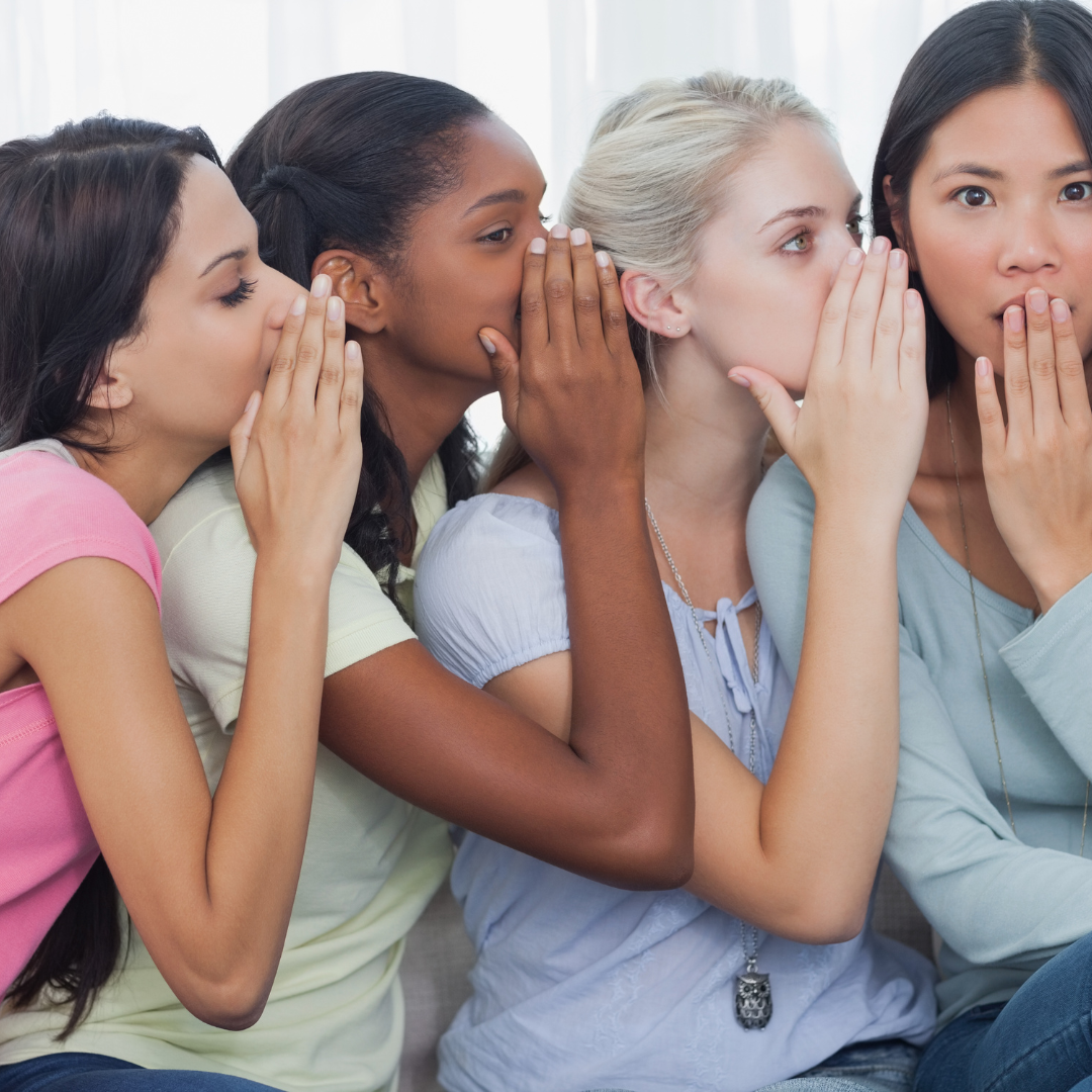 4 women of various ethnicities whispering to each other